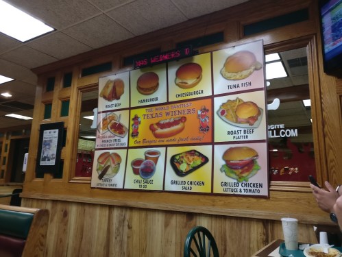 Menu board featuring various food items like burgers, hot dogs, and salads at a diner. Bright colors and playful design.