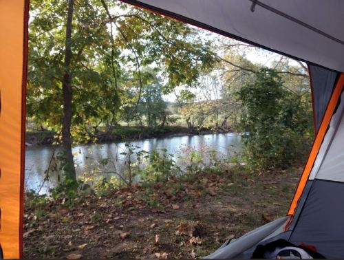 View from inside a tent, showcasing a serene river and lush trees outside.