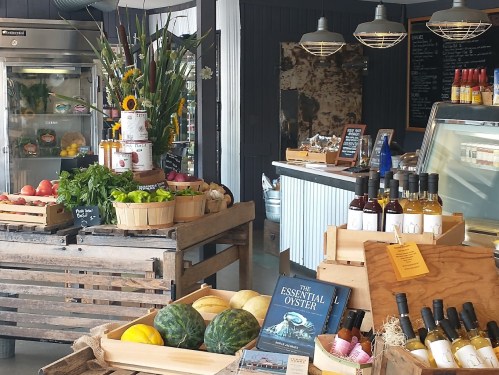 A vibrant market display with fresh produce, flowers, and bottles of wine, showcasing a cozy, inviting atmosphere.
