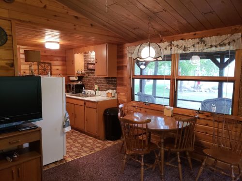Cozy wooden cabin interior featuring a kitchen, dining area, and large windows with a view of the outdoors.
