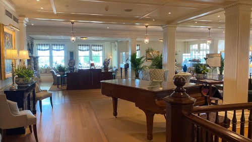 Elegant interior of a hotel lobby featuring a grand piano, seating areas, and large windows with natural light.