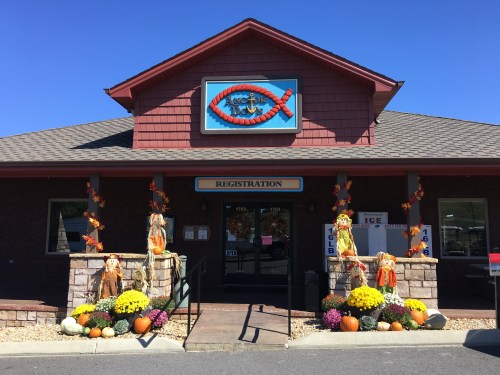 A building with a sign reading "Registration," decorated with fall flowers and scarecrows at the entrance.