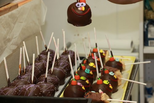 A variety of chocolate-covered treats on sticks, decorated with colorful toppings and faces, ready for serving.