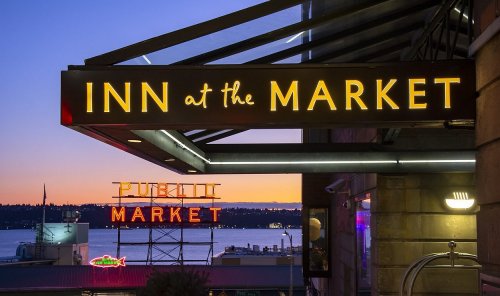 Sign for "Inn at the Market" with the "Pike Place Market" sign in the background at sunset.