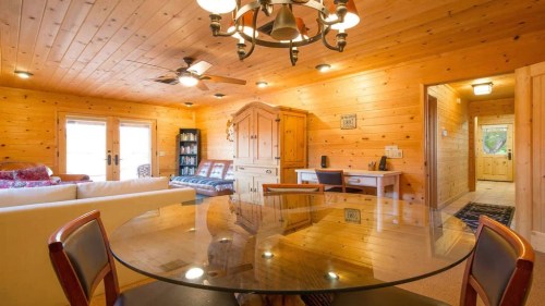 Cozy wooden interior featuring a dining table, living area, and a hallway leading to other rooms.