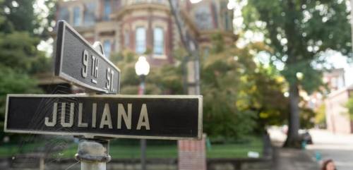 Street sign for Juliana Street with a historic building in the background, surrounded by trees and greenery.