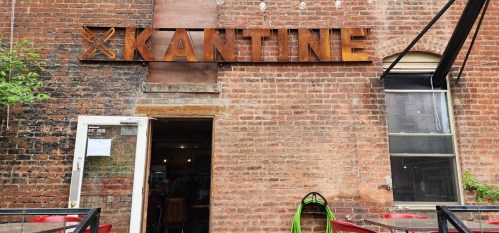 Exterior of a restaurant named "Kantine," featuring a brick wall and a welcoming entrance.