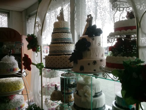 A display of elegant wedding cakes in a bakery, featuring intricate designs and floral decorations.