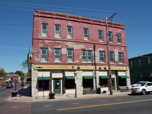 Historic red brick building with large windows, featuring a restaurant on the ground floor and a clear blue sky above.