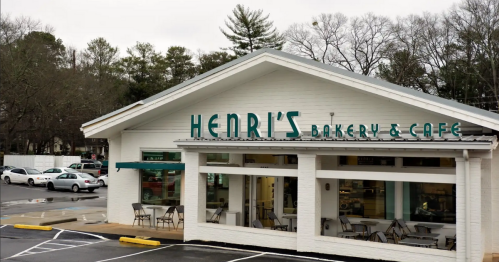 Exterior of Henri's Bakery & Café, featuring a white building with green signage and outdoor seating.