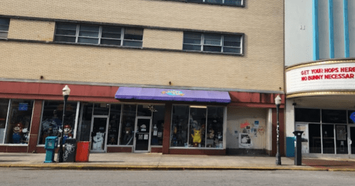A storefront with a purple awning, featuring colorful decorations and a marquee sign above.