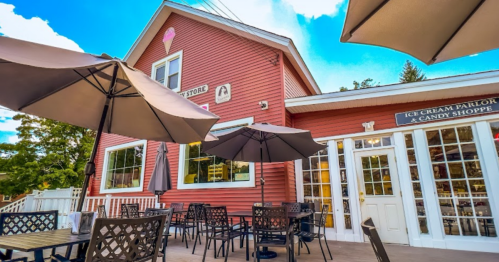 A charming pink ice cream parlor with outdoor seating and umbrellas on a sunny day.