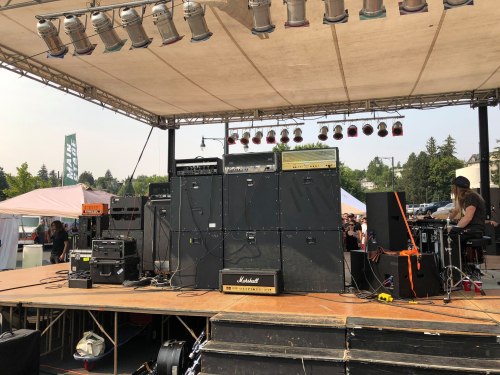 A stage setup with amplifiers and instruments, ready for a performance at an outdoor event.