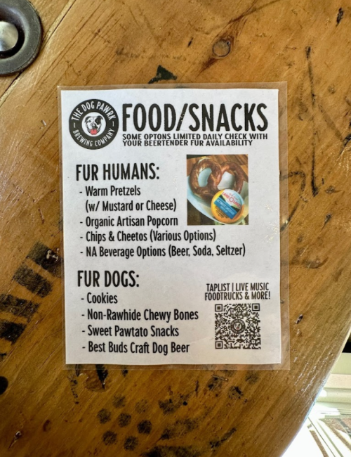 Menu for food and snacks, including options for humans and dogs, on a wooden table.