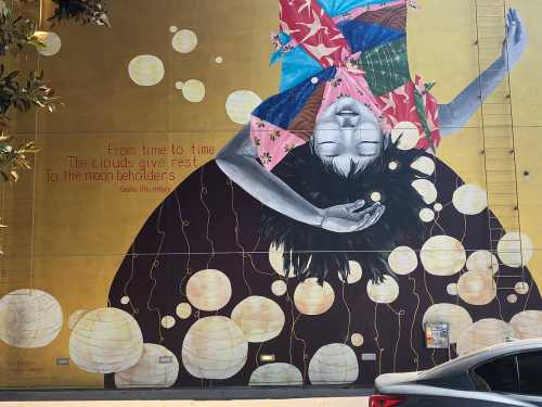 A vibrant mural of a girl floating with lanterns, featuring a quote about clouds and moon beholders.