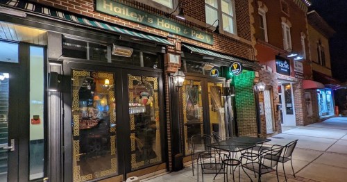 Exterior of Hailey's Harp & Pub at night, featuring decorative doors and outdoor seating.
