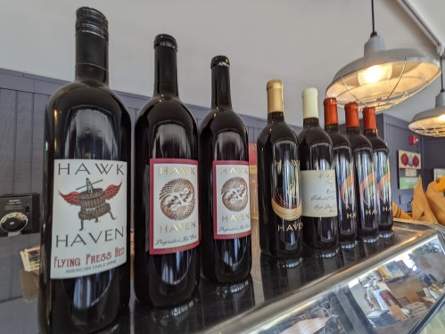 A row of wine bottles labeled "Hawk Haven" displayed on a counter in a cozy setting.