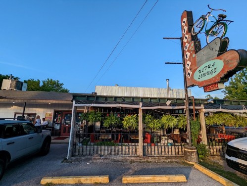 A lively restaurant exterior with a vintage sign, bike decor, and outdoor seating under a clear blue sky.