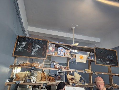 A bakery counter with menus for ordering and pickup, featuring various baked goods and pastries displayed.
