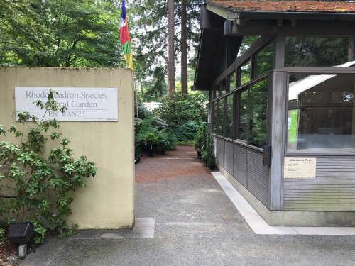 Entrance to the Rhododendron Species Botanical Garden, featuring a pathway and greenery on either side.