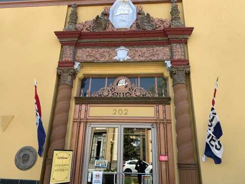 Historic building entrance with ornate architecture, featuring flags and a sign that reads "Open."