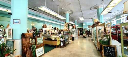 A spacious antique shop with various displays, vintage items, and decorative plants under bright lighting.