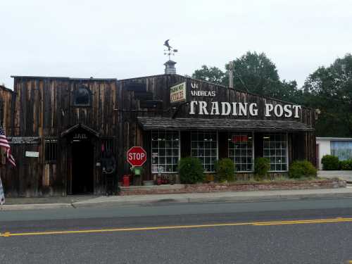 A rustic trading post with wooden exterior, large sign, and a jail entrance, set along a quiet road.