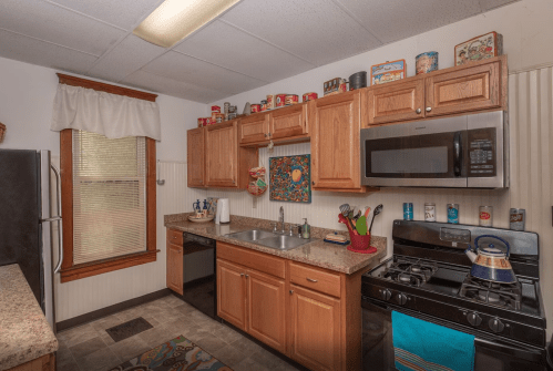 Cozy kitchen with wooden cabinets, stainless steel appliances, and colorful decor on the walls and shelves.