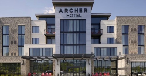 Modern Archer Hotel exterior featuring large windows and a welcoming entrance with outdoor seating.