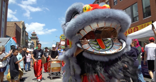 A colorful lion dance performance in a street festival, with performers in traditional costumes and a vibrant blue lion head.