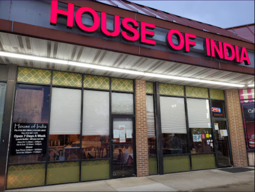 Exterior of "House of India" restaurant with red signage, open hours displayed, and large windows.