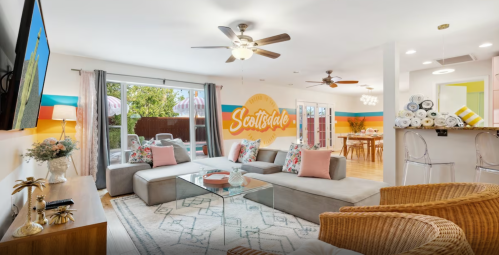 Bright living room with a large sectional sofa, colorful wall art, and a dining area in the background. Cozy and inviting atmosphere.