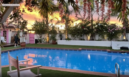 A serene poolside view at sunset, surrounded by lush greenery and colorful flowers.