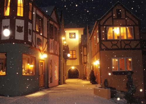 Charming snow-covered street with colorful, illuminated buildings and a cozy atmosphere at night.
