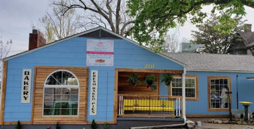 A blue bakery with wooden accents, featuring a sign that reads "Fresh Baked Pies" and a welcoming porch.