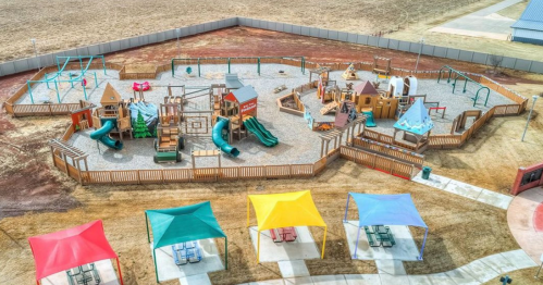Aerial view of a colorful playground with slides, climbing structures, and shaded picnic areas.