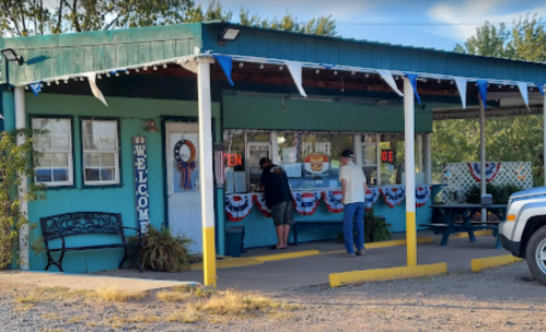 A small, colorful building with a welcoming sign, featuring patriotic decorations and two people at a service window.