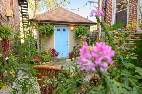 A charming garden with vibrant flowers and a light blue door in a cozy outdoor space.