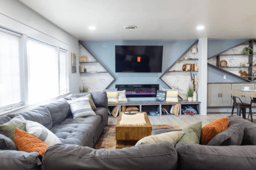 Cozy living room with a sectional sofa, modern decor, a wall-mounted TV, and an electric fireplace.