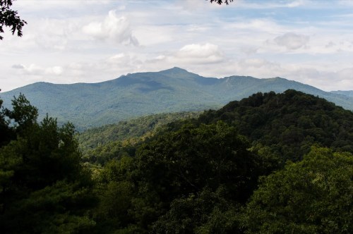 A scenic view of lush green mountains under a partly cloudy sky.
