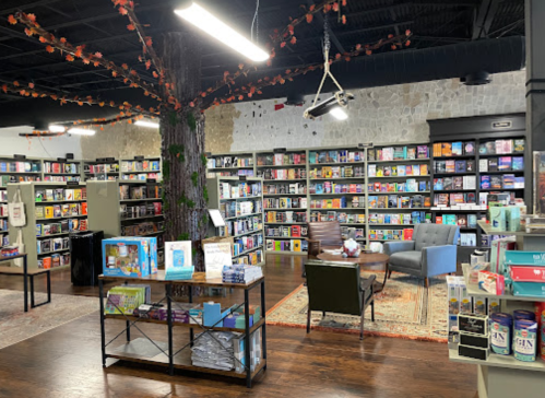 A cozy bookstore interior with shelves of books, a reading area, and decorative tree elements.