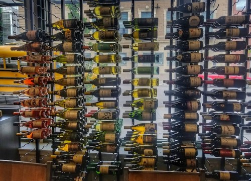 A wall display of various wine bottles arranged in a modern setting, showcasing different colors and labels.