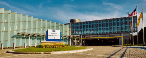 Exterior view of the CDC Museum, featuring modern architecture and flags, with a clear blue sky in the background.