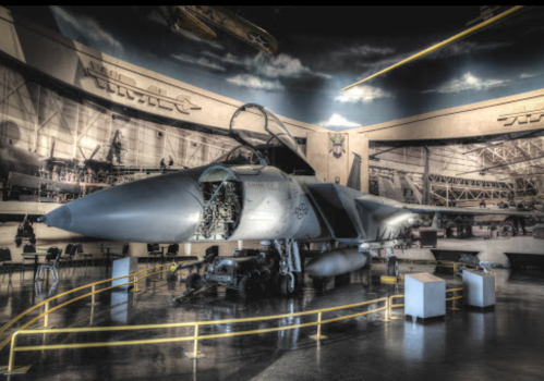 A military jet displayed indoors, showcasing its open cockpit and detailed interior against a backdrop of aviation history.