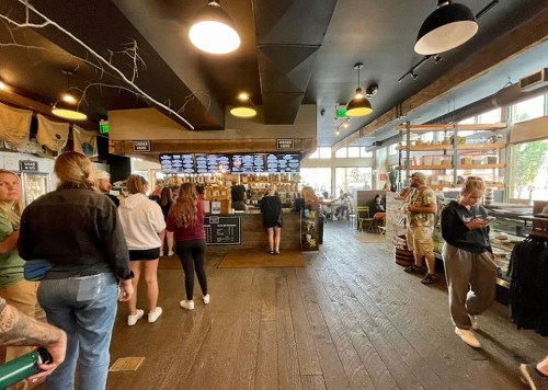 A busy café interior with a counter, customers ordering, and a mix of seating areas and decor.