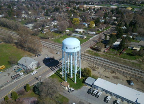 Aerial view of a water tower labeled "BLACKFOOT" surrounded by residential areas and railway tracks.