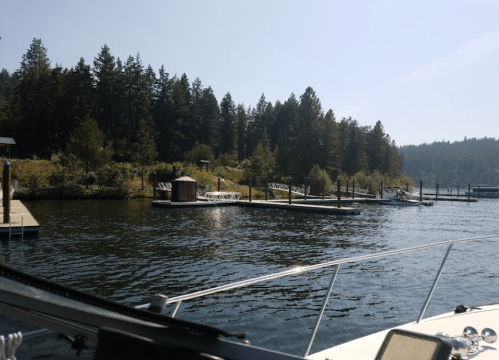 A view of a calm lake with docks and trees lining the shore under a clear blue sky.