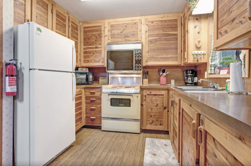 A cozy kitchen with wooden cabinets, a white refrigerator, an oven, and various appliances on the counter.