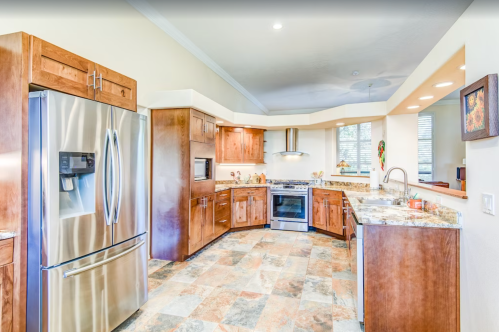 Modern kitchen with wooden cabinets, stainless steel appliances, and granite countertops, featuring a spacious layout.