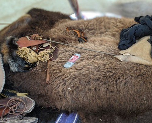 A cozy scene featuring a bear fur rug, leather items, and a small bottle on a textured surface.
